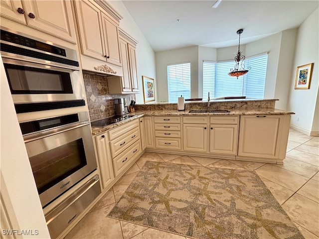 kitchen featuring decorative backsplash, a peninsula, black electric cooktop, cream cabinetry, and a sink