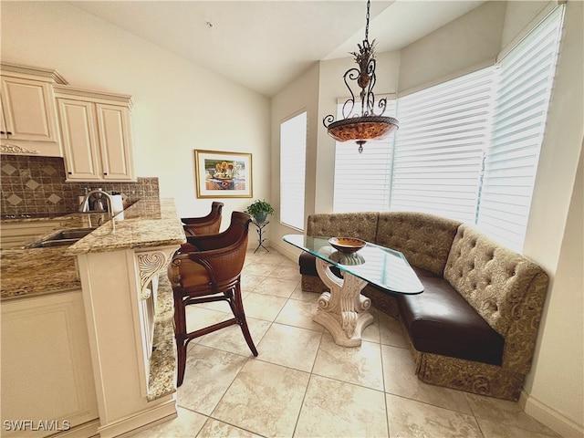 dining space with baseboards, breakfast area, vaulted ceiling, and light tile patterned flooring