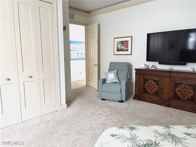 carpeted bedroom with ornamental molding and a closet