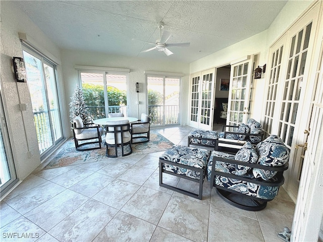 sunroom / solarium featuring a healthy amount of sunlight, a ceiling fan, and french doors