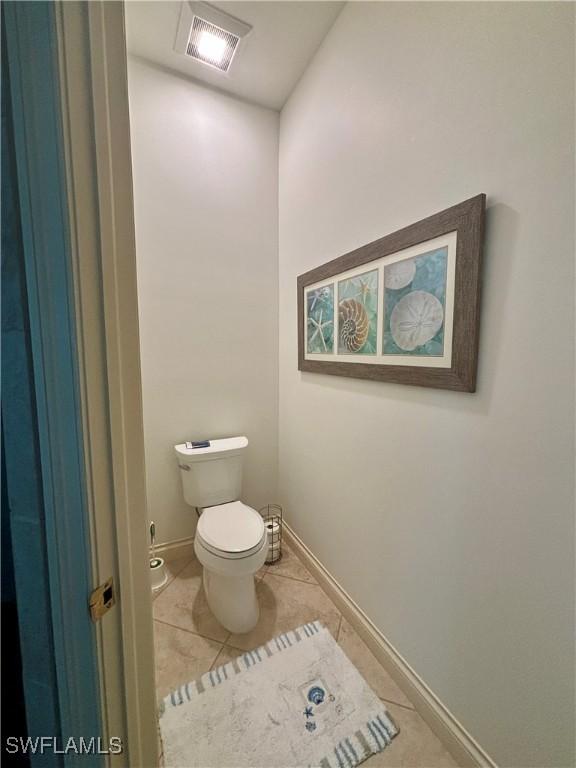 bathroom with tile patterned flooring, baseboards, visible vents, and toilet