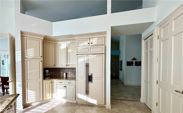 kitchen with light stone counters, tasteful backsplash, cream cabinets, light tile patterned flooring, and paneled refrigerator