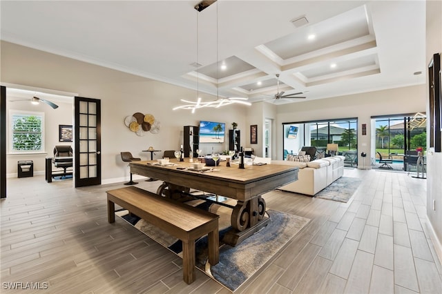 dining space featuring coffered ceiling, crown molding, ceiling fan with notable chandelier, and a high ceiling