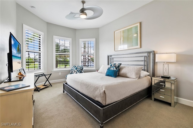 bedroom featuring ceiling fan, light colored carpet, and multiple windows