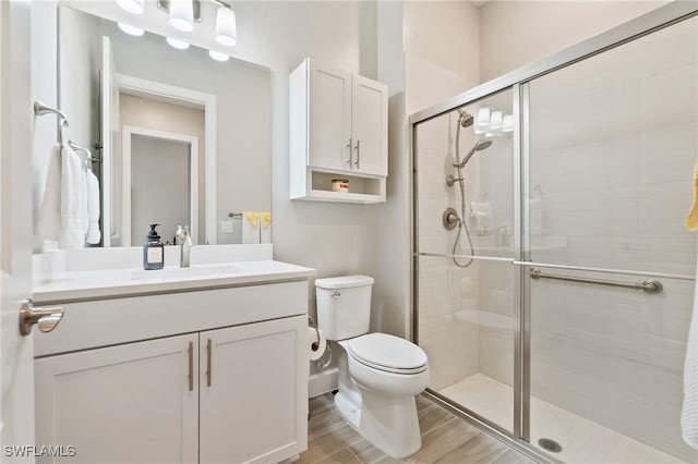 bathroom with vanity, toilet, an enclosed shower, and hardwood / wood-style floors