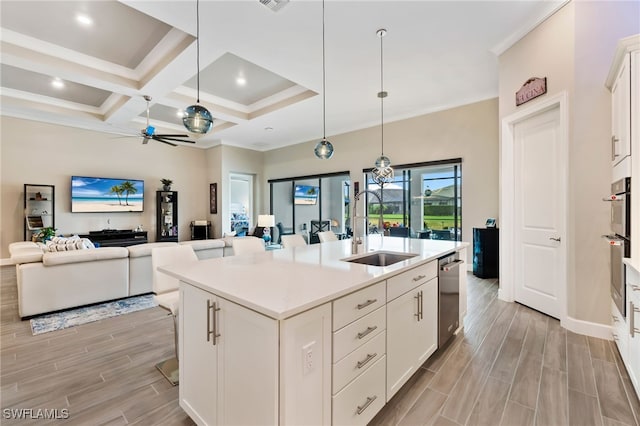 kitchen featuring pendant lighting, crown molding, a breakfast bar area, white cabinetry, and a center island with sink