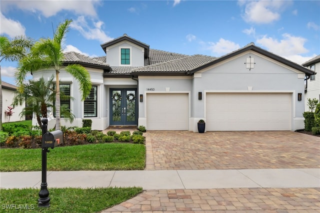 mediterranean / spanish-style home with a front lawn, a garage, and french doors