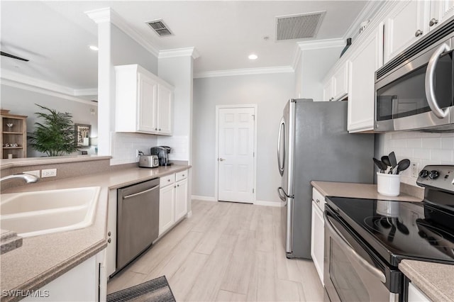 kitchen featuring sink, white cabinetry, crown molding, light wood-type flooring, and stainless steel appliances