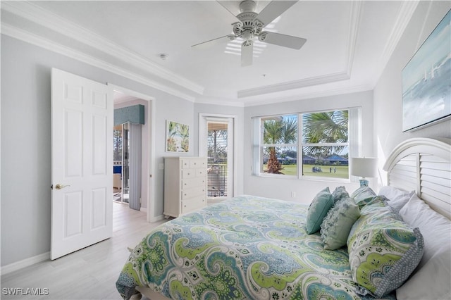 bedroom with a tray ceiling, crown molding, light hardwood / wood-style floors, and ceiling fan