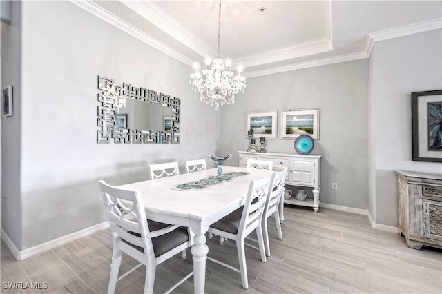 dining room with ornamental molding, a tray ceiling, and a notable chandelier