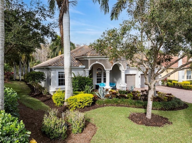 mediterranean / spanish home featuring a front lawn and a garage