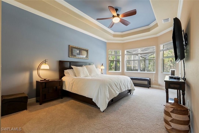 carpeted bedroom with ceiling fan, ornamental molding, and a tray ceiling