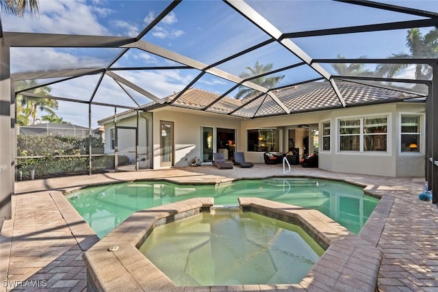 view of pool with an in ground hot tub, a patio area, and glass enclosure