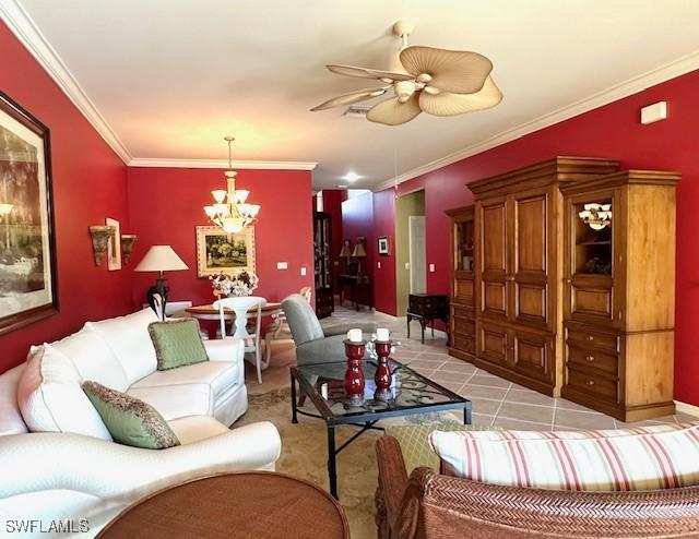 living room with crown molding, light tile patterned floors, and ceiling fan with notable chandelier