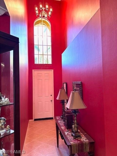 tiled foyer entrance featuring a chandelier and a high ceiling