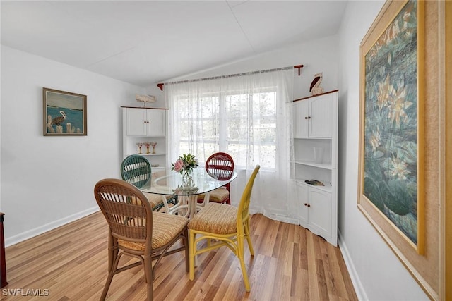 dining space featuring vaulted ceiling and light hardwood / wood-style flooring