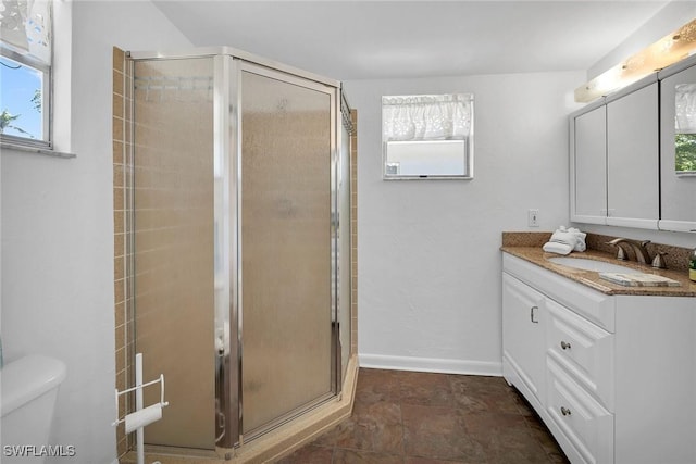 bathroom featuring a shower with shower door, vanity, and toilet