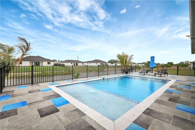 view of pool featuring a residential view, a patio area, fence, and a fenced in pool