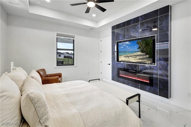 bedroom featuring a tray ceiling, a fireplace, and ceiling fan