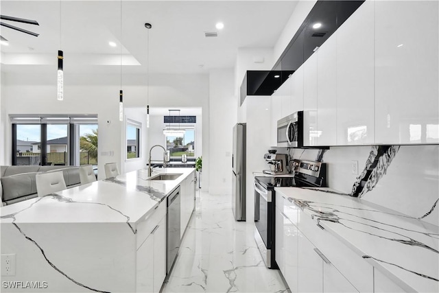 kitchen with pendant lighting, sink, appliances with stainless steel finishes, a spacious island, and white cabinets