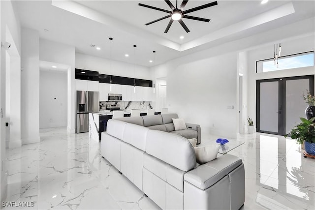 living room featuring french doors, ceiling fan, a raised ceiling, and a towering ceiling