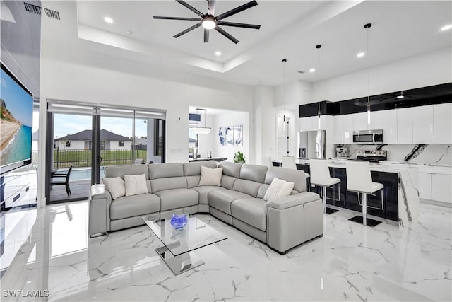 living area featuring visible vents, a raised ceiling, a towering ceiling, and recessed lighting