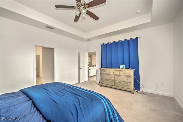 carpeted bedroom with ceiling fan and a tray ceiling