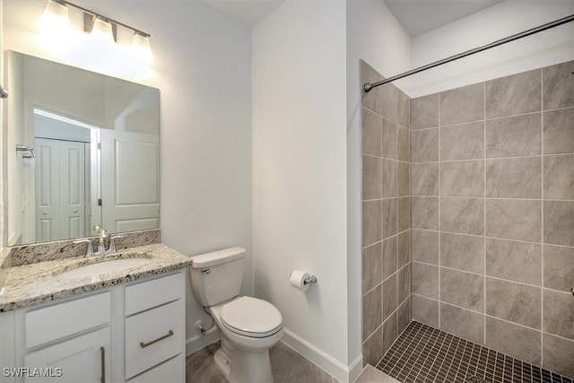 bathroom with vanity, toilet, and tiled shower