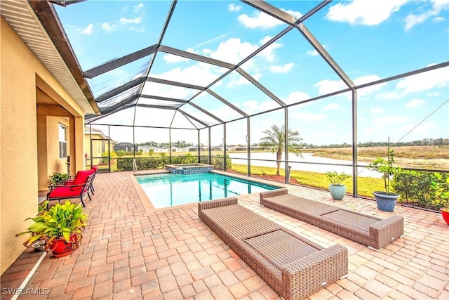 view of pool featuring an in ground hot tub, a water view, glass enclosure, and a patio area