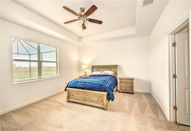 bedroom with light carpet, a raised ceiling, and ceiling fan