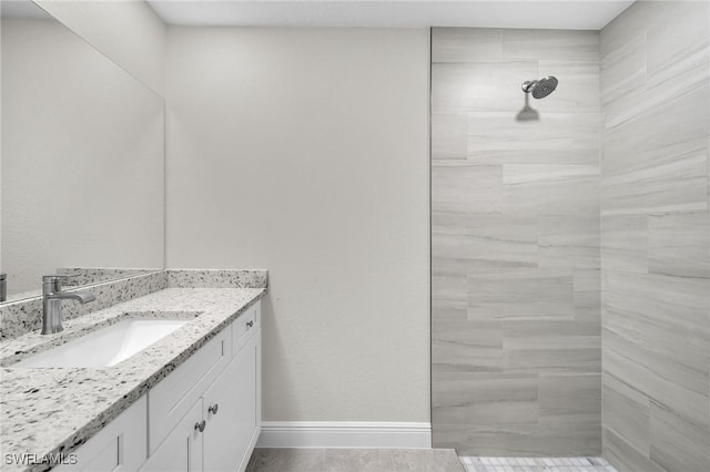 bathroom with tiled shower, vanity, and tile patterned flooring