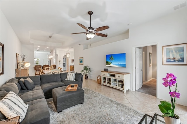 tiled living room featuring ceiling fan and a tray ceiling