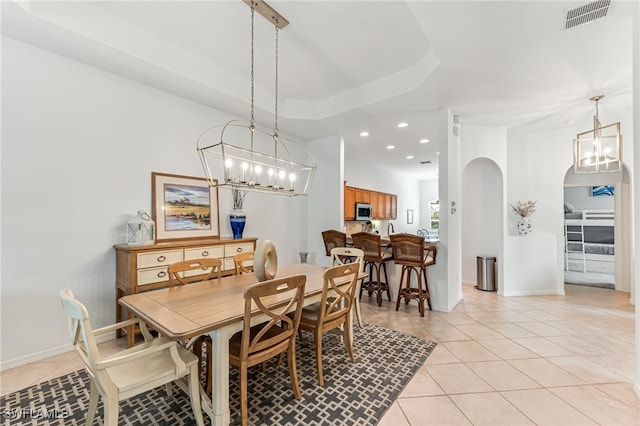 tiled dining space with a tray ceiling and a notable chandelier