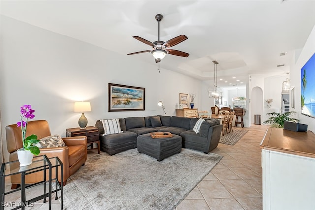 living room featuring ceiling fan, light tile patterned floors, and a tray ceiling