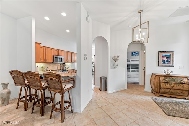 kitchen featuring a high ceiling, decorative light fixtures, a kitchen bar, an inviting chandelier, and kitchen peninsula