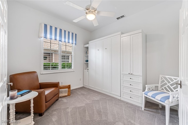 sitting room with ceiling fan and light colored carpet