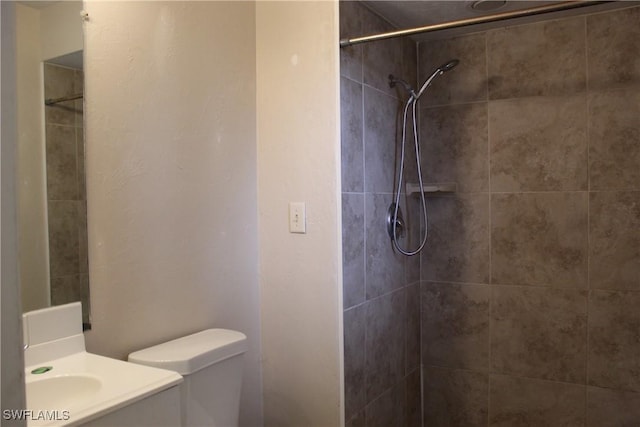 bathroom with toilet, vanity, and a tile shower