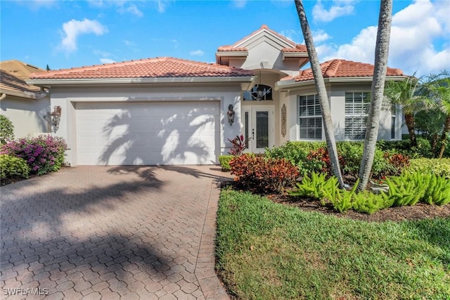 14113 Tivoli Ter, Bonita Springs, FL 34135 - mediterranean / spanish-style home with a garage, stucco siding, decorative driveway, a tile roof, and french doors