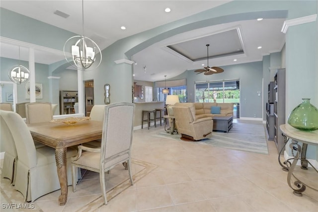 tiled dining area featuring ceiling fan with notable chandelier, ornamental molding, a raised ceiling, and a healthy amount of sunlight