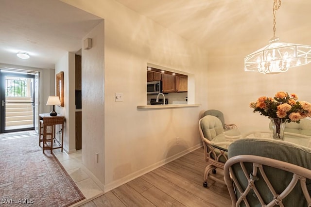 dining space with light hardwood / wood-style floors and a notable chandelier