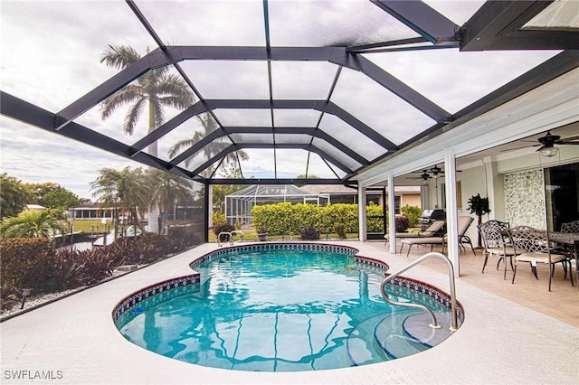 view of swimming pool with ceiling fan, glass enclosure, and a patio