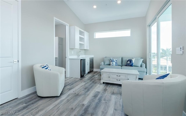 living room featuring vaulted ceiling, a healthy amount of sunlight, light hardwood / wood-style floors, and sink