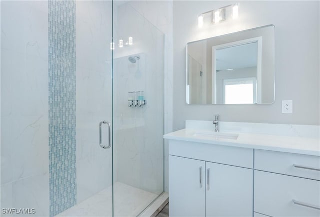 bathroom featuring a shower with shower door and vanity