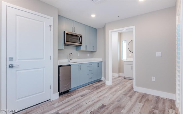 kitchen with dishwasher, sink, and light hardwood / wood-style flooring