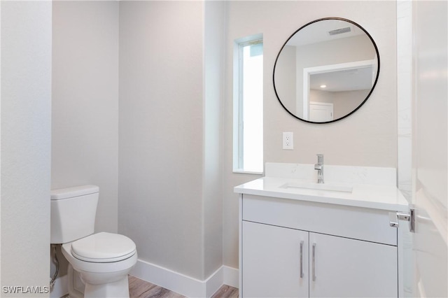 bathroom with toilet, hardwood / wood-style flooring, and vanity