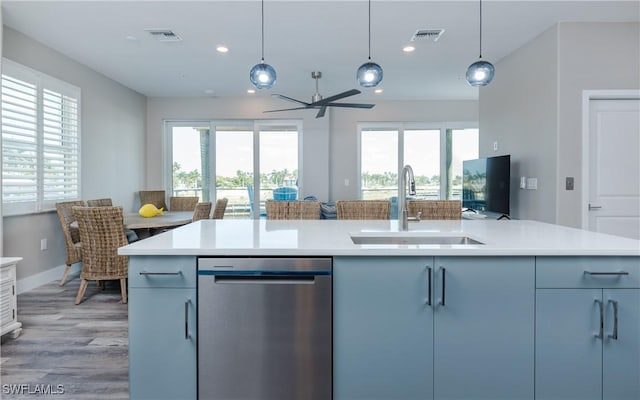 kitchen featuring sink, pendant lighting, stainless steel dishwasher, and a kitchen island with sink