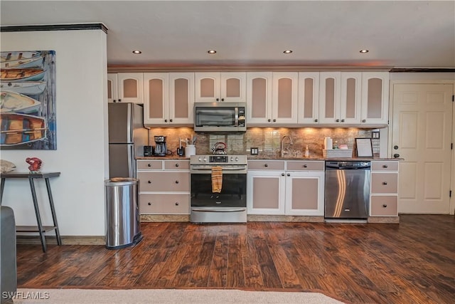 kitchen with decorative backsplash, white cabinetry, appliances with stainless steel finishes, and dark hardwood / wood-style flooring