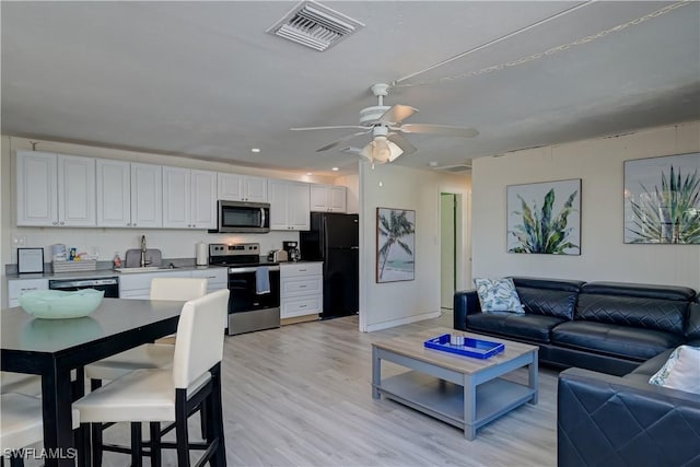 kitchen featuring black appliances, light wood-type flooring, white cabinetry, and ceiling fan