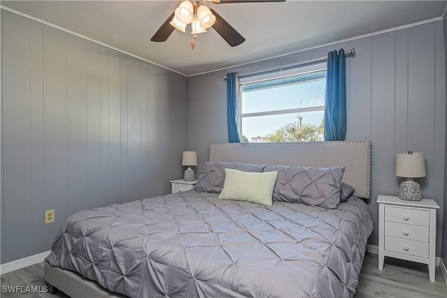 bedroom with ceiling fan, ornamental molding, wood walls, and light wood-type flooring