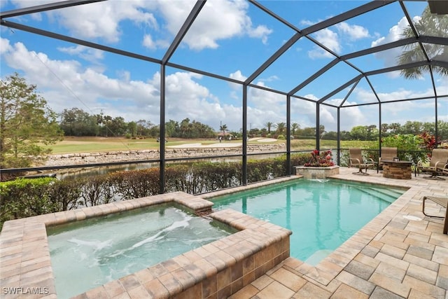 view of swimming pool featuring glass enclosure, a fire pit, a water view, an in ground hot tub, and a patio